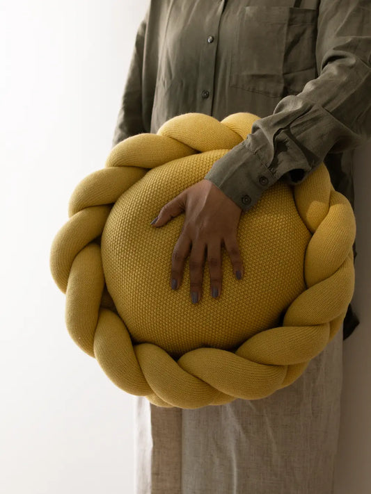 Close-up texture of yellow cotton knit cushion and braided detailing
