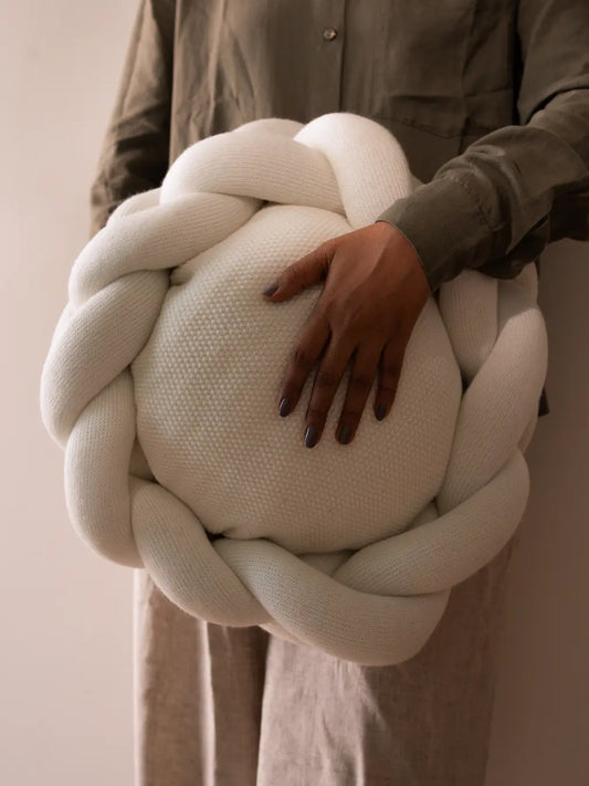 Gharko white braided wool cushion held in hand