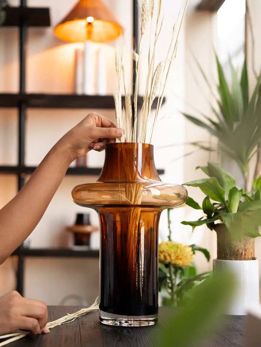 Person interacting with a decorative vase on a table with a blurred background