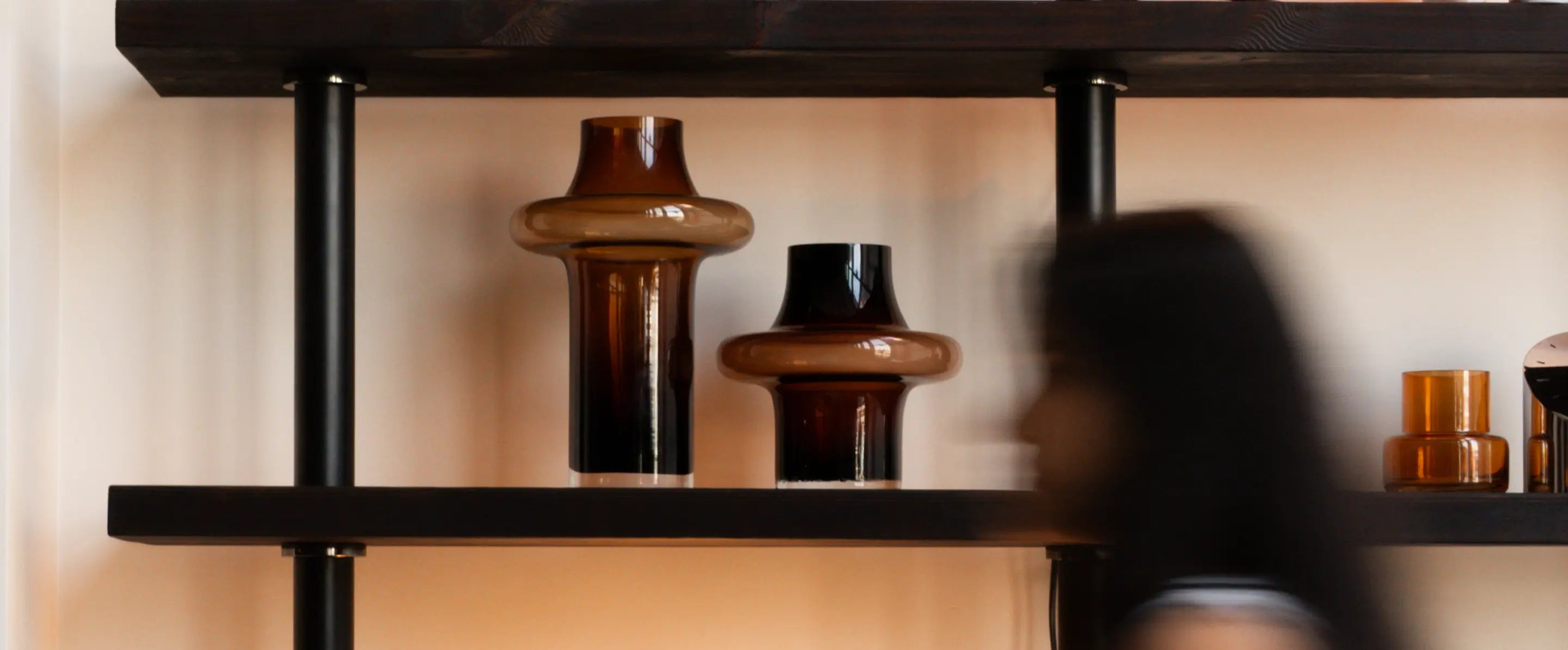 Large and small Halo Amber Glass Vases on shelf in modern living room with warm amber decor accents.