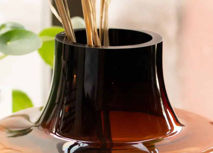 Close up of Halo Amber Glass Vase Small rim with dried stems and green indoor plant behind.