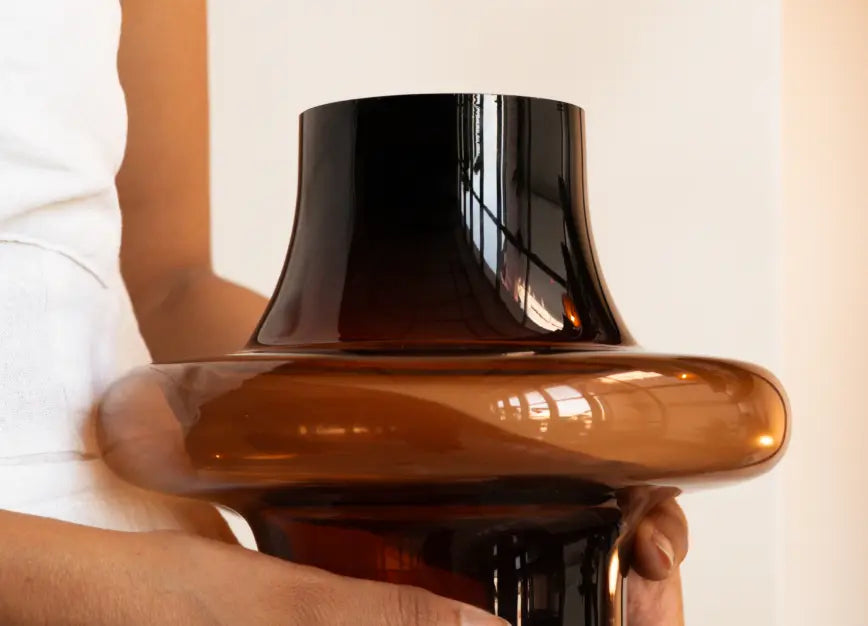 Person holding Halo Amber Glass Vase, highlighting glossy amber glass and sculptural halo shape.
