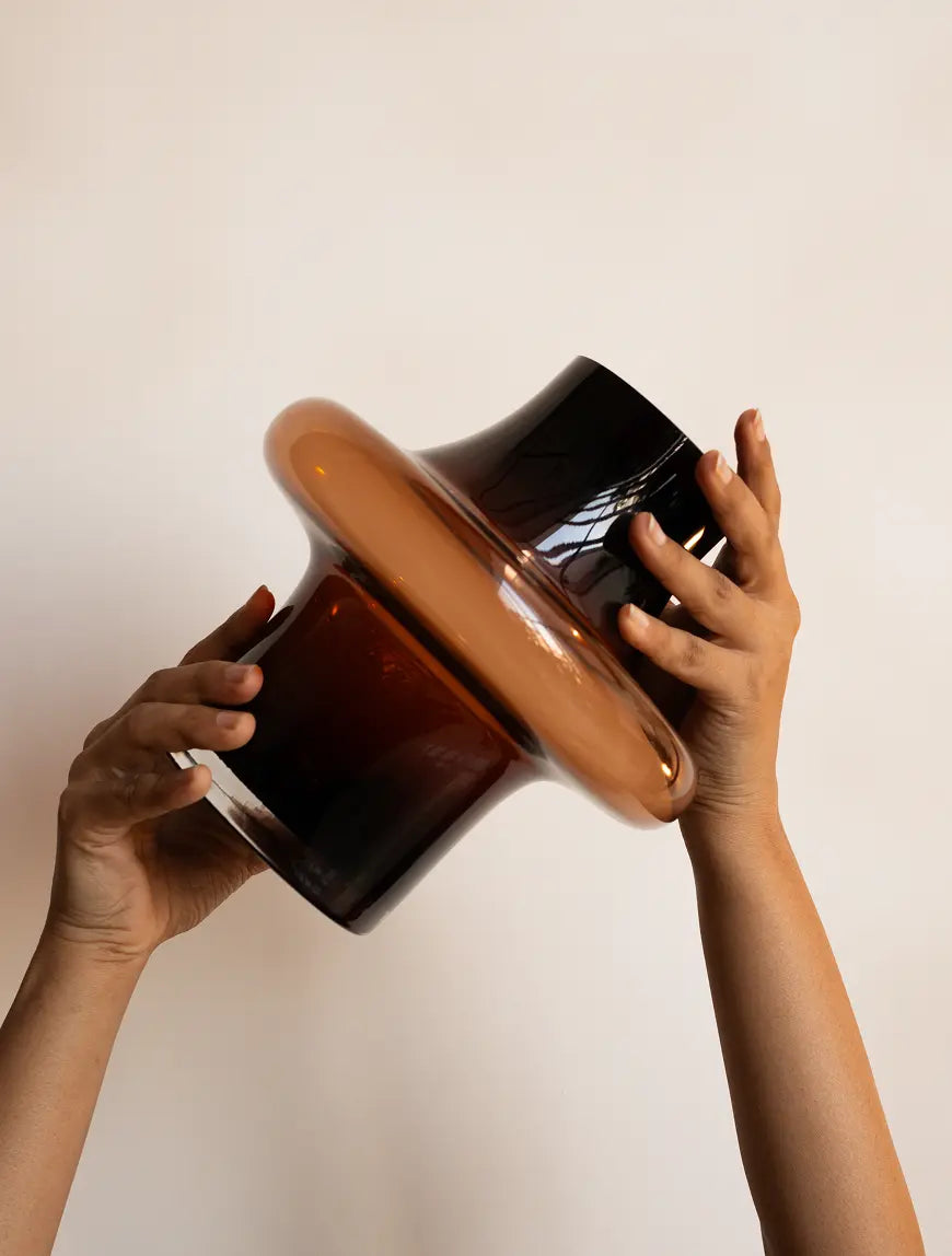 Hands lifting Halo Amber Glass Vase to show premium amber glass finish and modern sculptural form.
