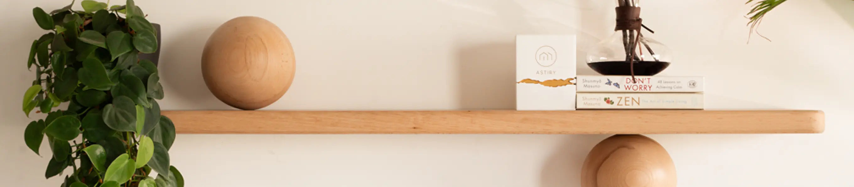 Japandi decor shelf with spherical balls, trailing plant, and minimalist home decor accessories