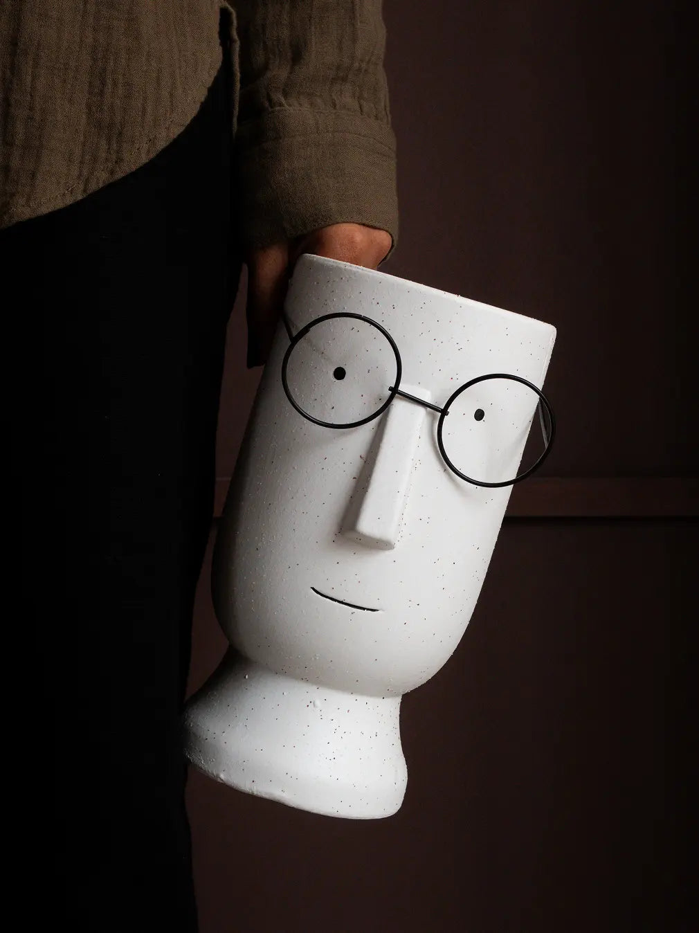 Jojo ceramic pot held by hand, showcasing playful face and premium ceramic finish