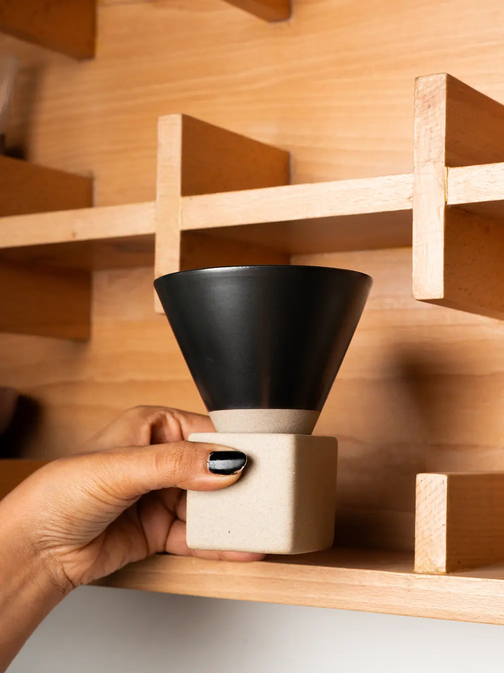 Hand holding black ceramic coffee cup with minimalist Japanese-inspired form