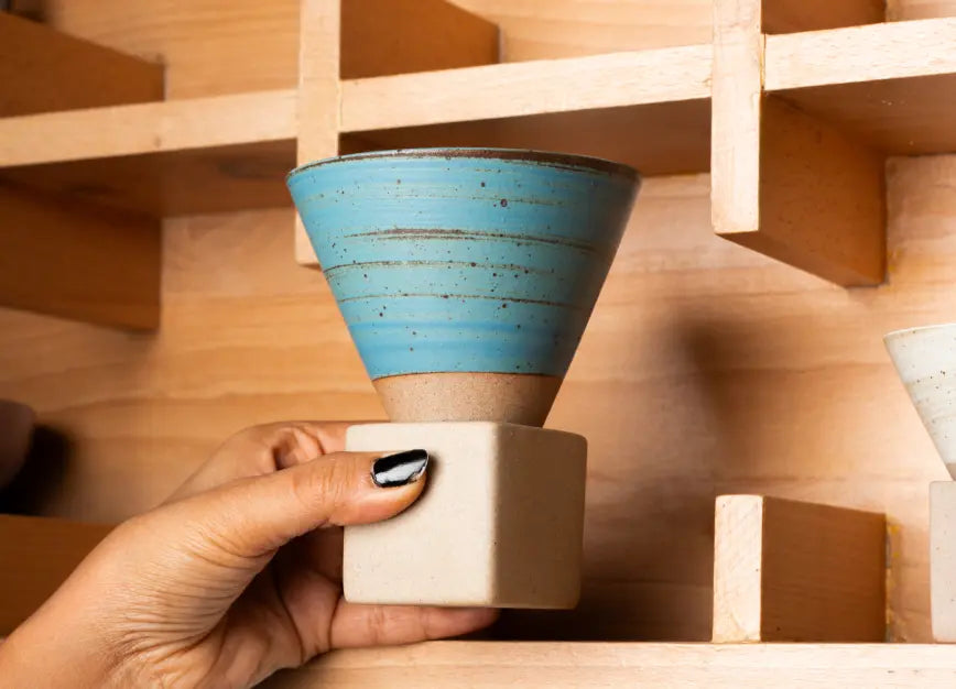 Handcrafted blue ceramic coffee cup placed on wooden shelf display
