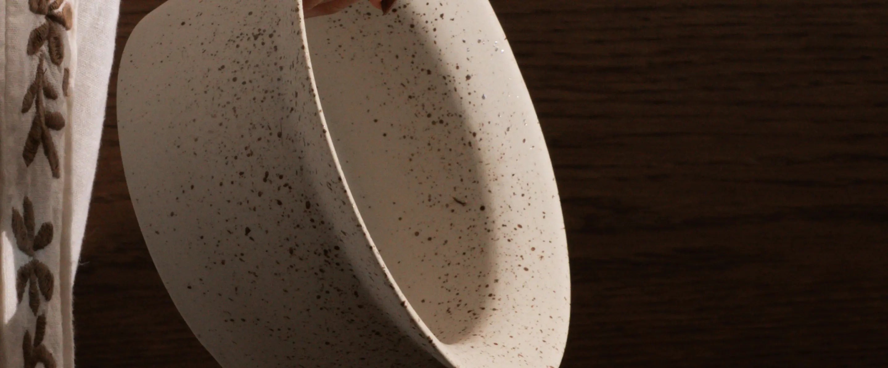 Kora Ceramic Planter being tilted, showcasing its premium ceramic build and speckled ink dot finish