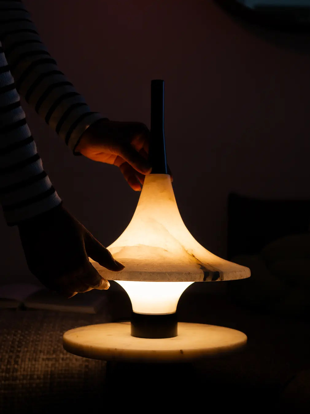 Person holding Gharko Lattu Marble Table Lamp in a dark setting