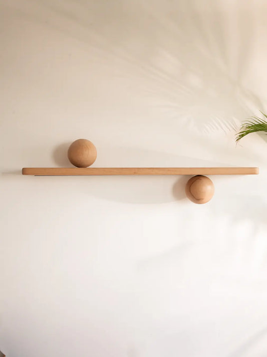 Wooden floating wall shelf with spherical wooden on a plain wall.