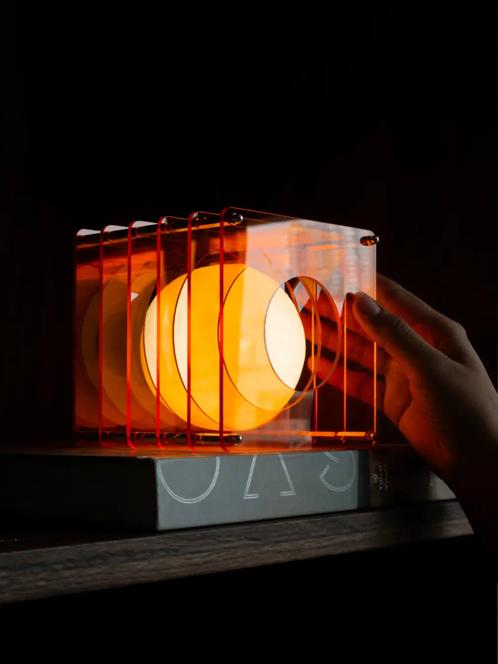 Lop portable table lamp glowing on shelf with layered acrylic frame design
