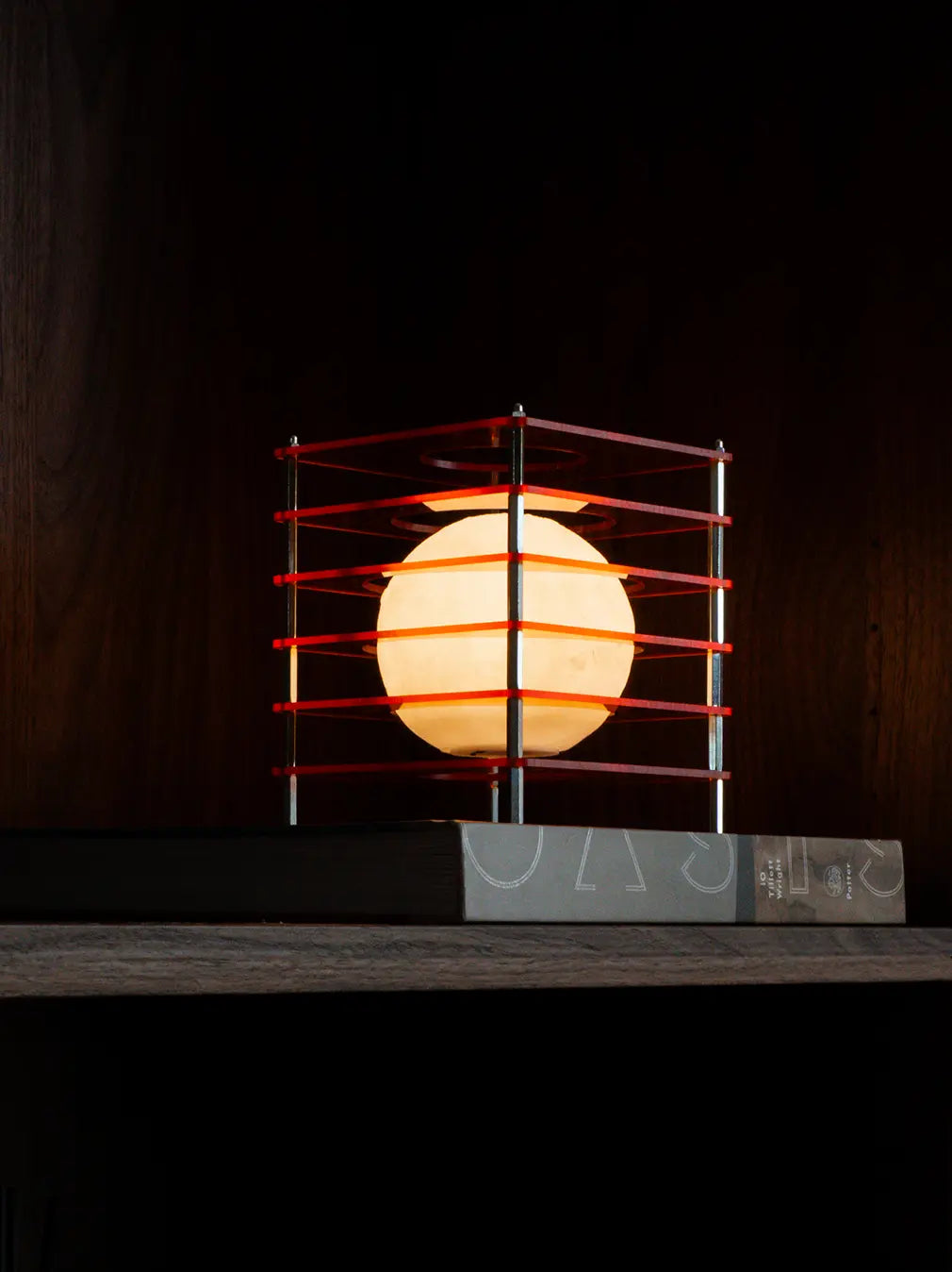 Modern Lop portable table lamp with acrylic layers and warm LED glow on shelf