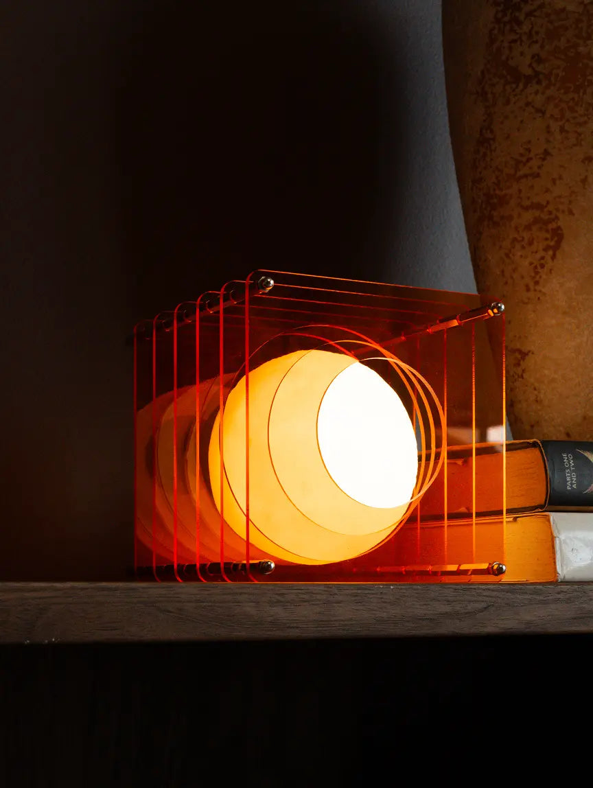 Lop portable table lamp with layered acrylic frame and warm LED glow on shelf