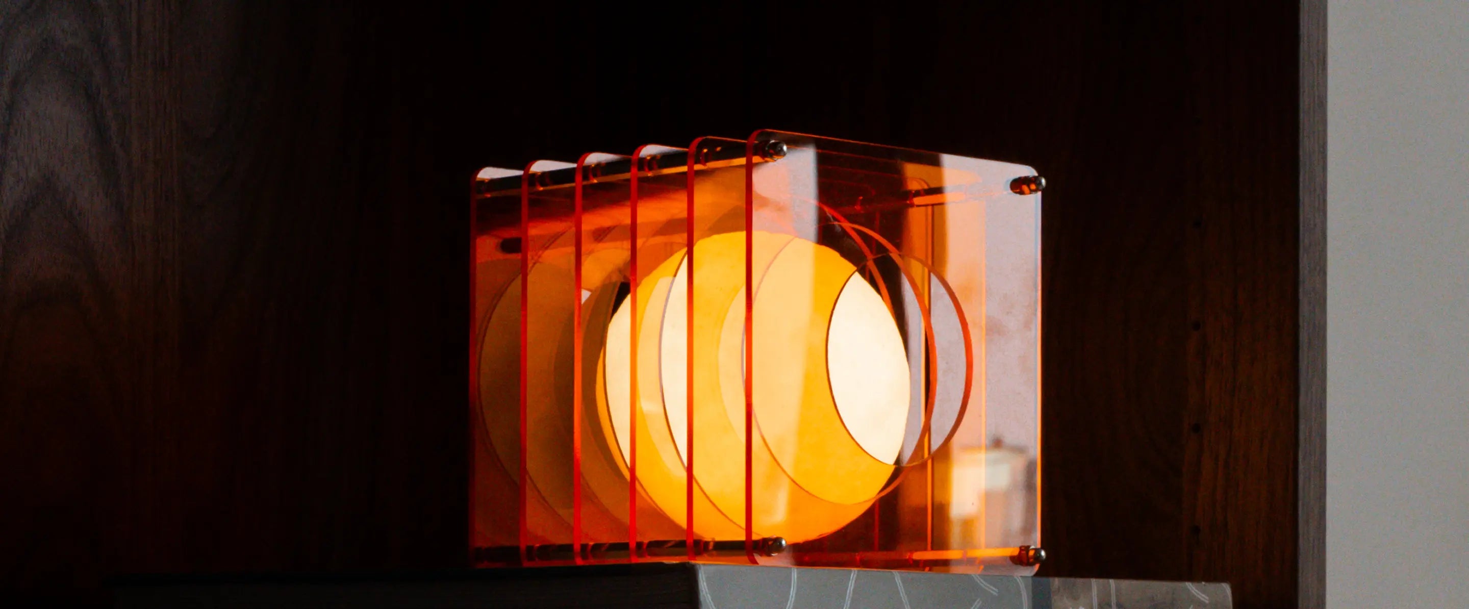 Wide view of Lop portable table lamp glowing inside layered acrylic frame