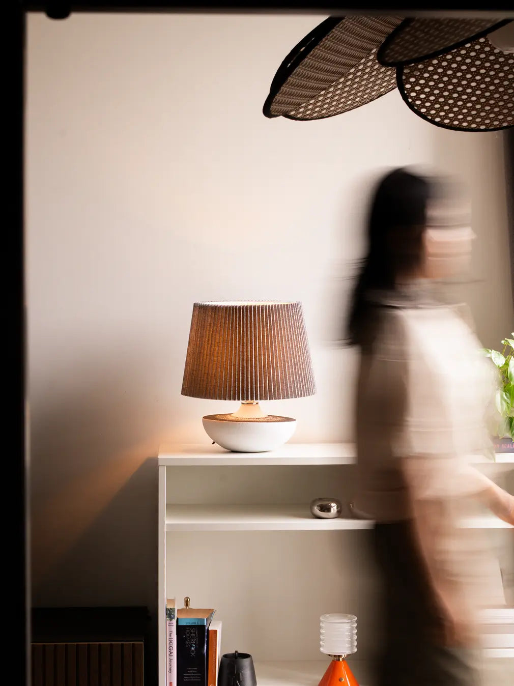 Modern Table Lamp on a shelf in living room with a blurred person in the foreground