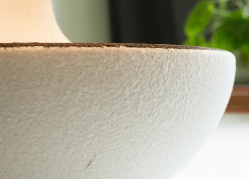 Close-up of a textured white ceramic lamp base with a blurred background