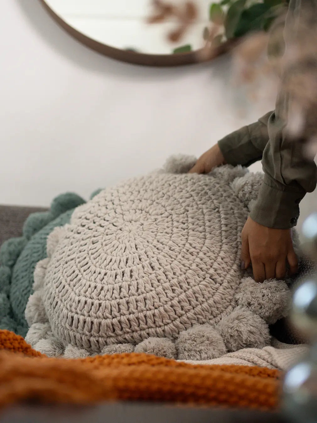 Placing a Gharko grey round cushion on sofa – decorative pillows for couch with soft knitted texture