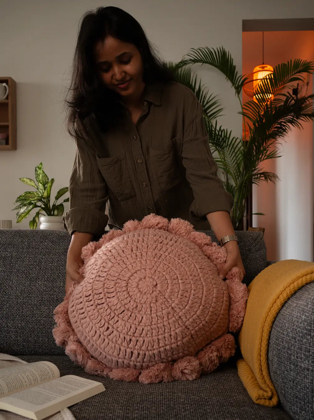 Woman holding a pink textured pillow in a living room setting