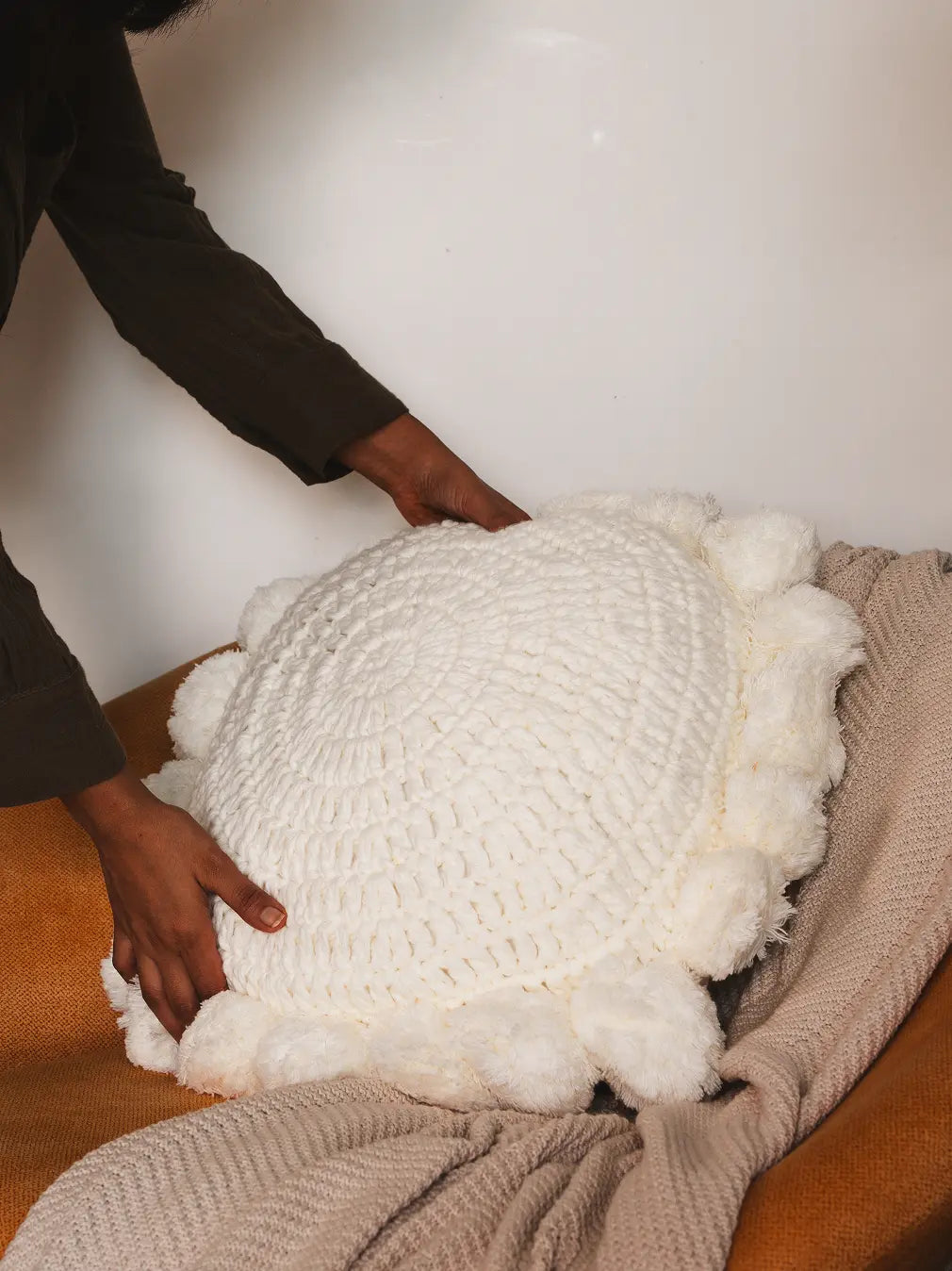 Person holding a textured white pillow on a chair