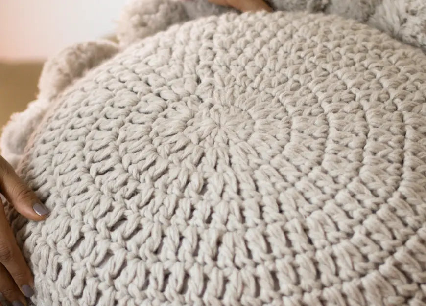 Close-up of a soft grey knitted cushion with textured detailing