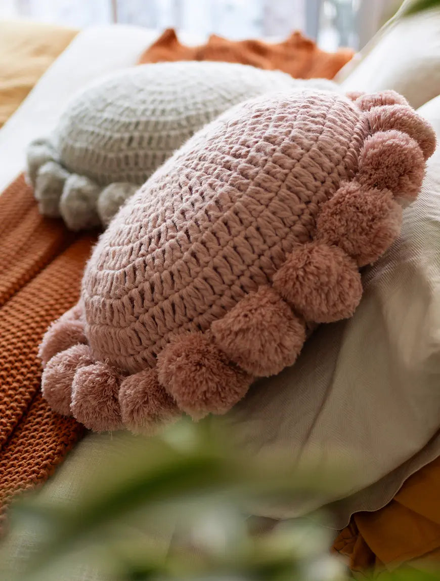 Gharko Knitted pillow with pom-poms on a soft surface