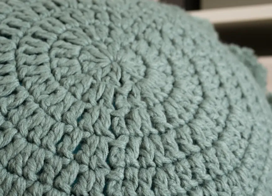 close up of Decorative round knitted cushion in turquoise blue 