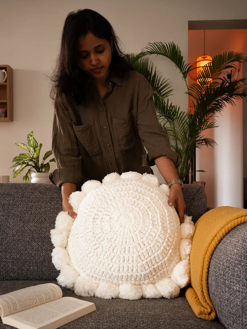 Woman holding a white textured pillow in a cozy living room.