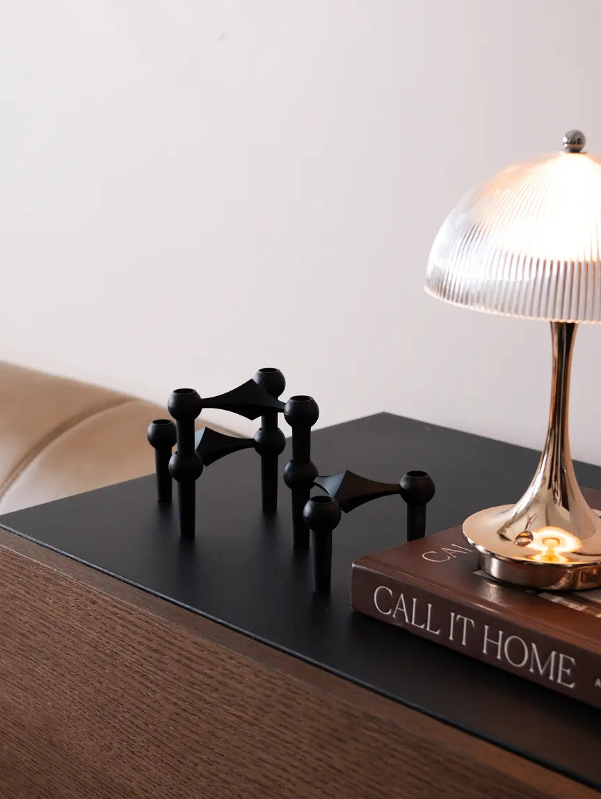Modular black candle holders styled on modern bedside table with ambient lamp glow