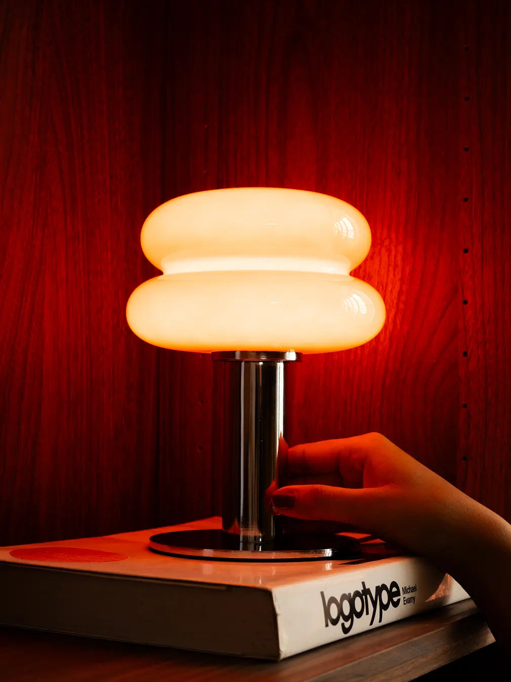 Illuminated Orbit Red portable table lamp casting a warm glow on a book