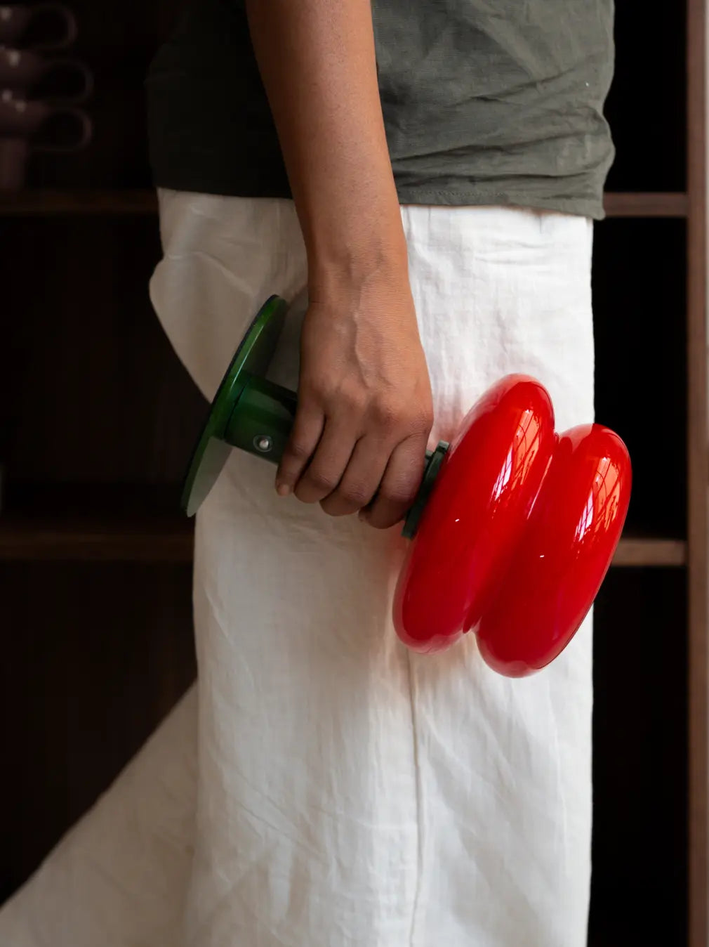 Orbit Red portable table lamp with green base carried by hand indoors