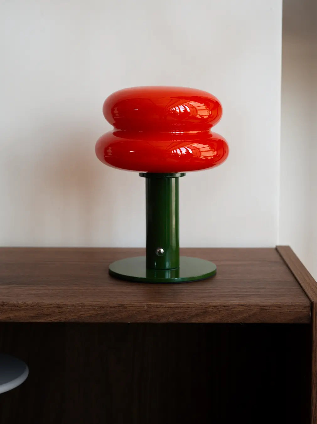 Orbit Red portable table lamp with green base styled on a wooden side table