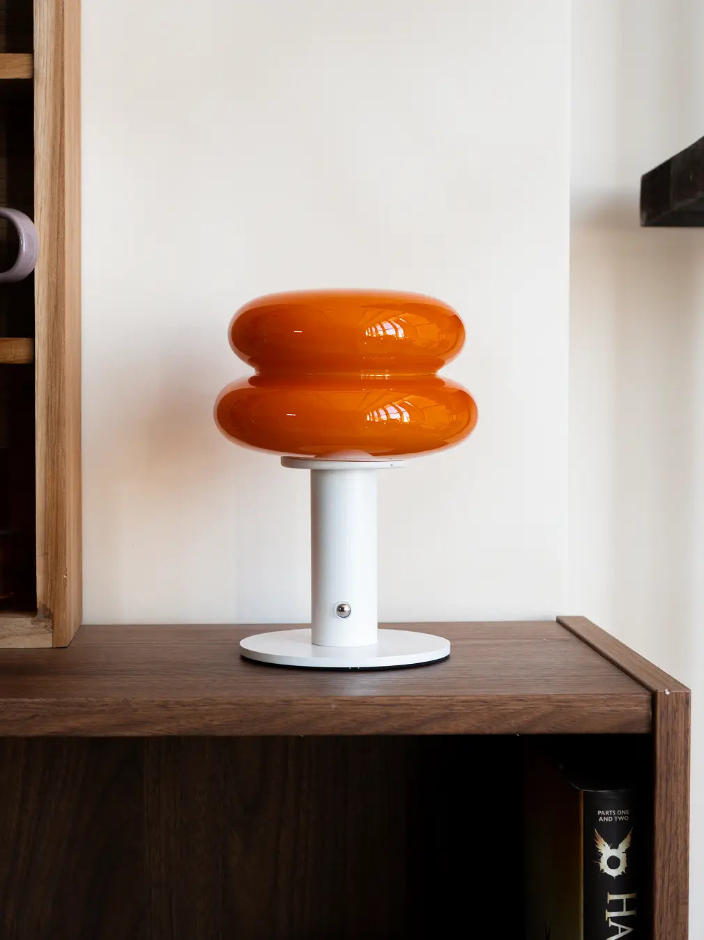 Modern orange portable lamp styled on shelf with sculptural contemporary design