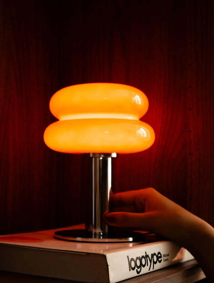 Illuminated Orbit Red table lamp with chrome base styled ond on a book