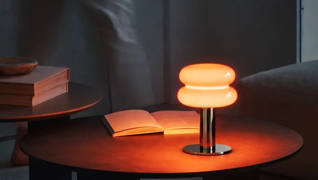 Orbit Red portable table lamp casting a warm glow beside an open book