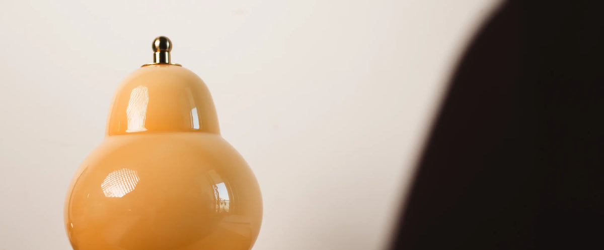 Close-up of a Pear Lamp with a metal top, reflecting soft natural light in a minimal space
