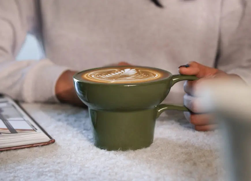 Olive Pico ceramic coffee mug filled with latte, showing sculpted form and wide rim