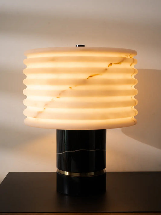 Ripple Marble Table Lamp glowing with warm ambient light on black table