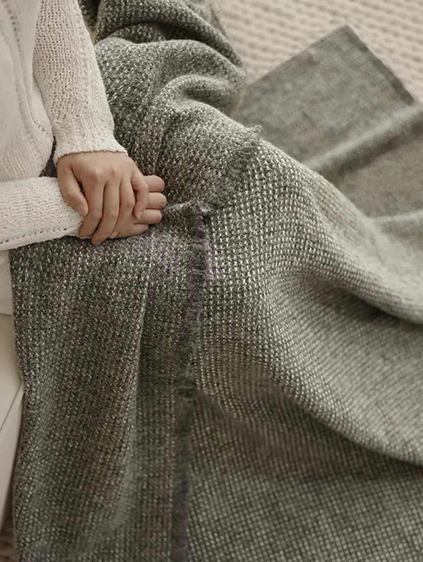 Person wrapped in Slate Angora throw blanket on sofa for cosy home comfort
