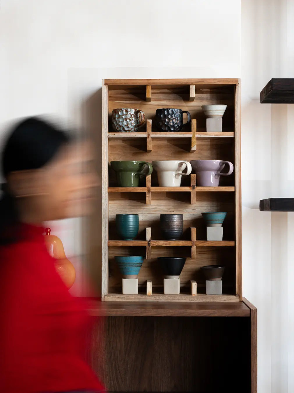Teak wood cup shelf with coffee mugs and cups displayed in a vertical wall-mounted rack