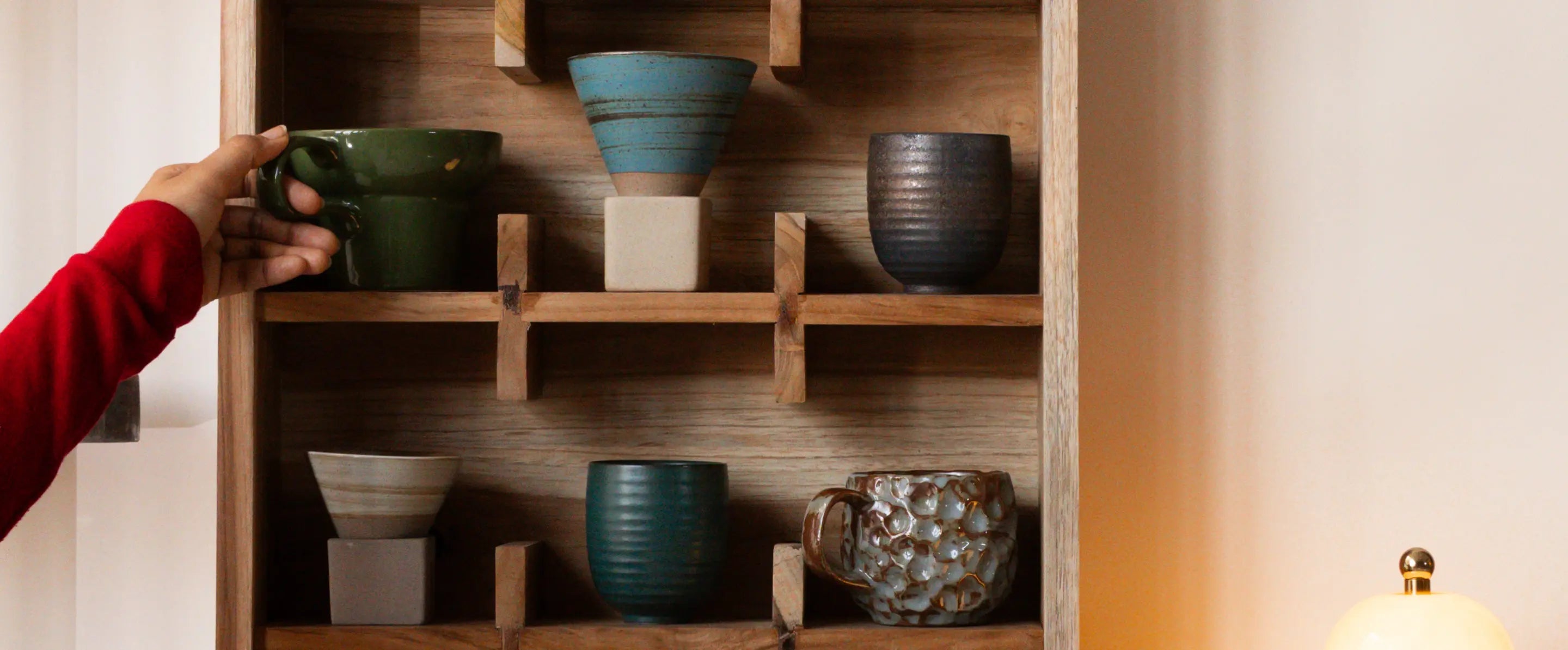 Coffee mugs displayed on teak wood wall mounted cup organizer shelf