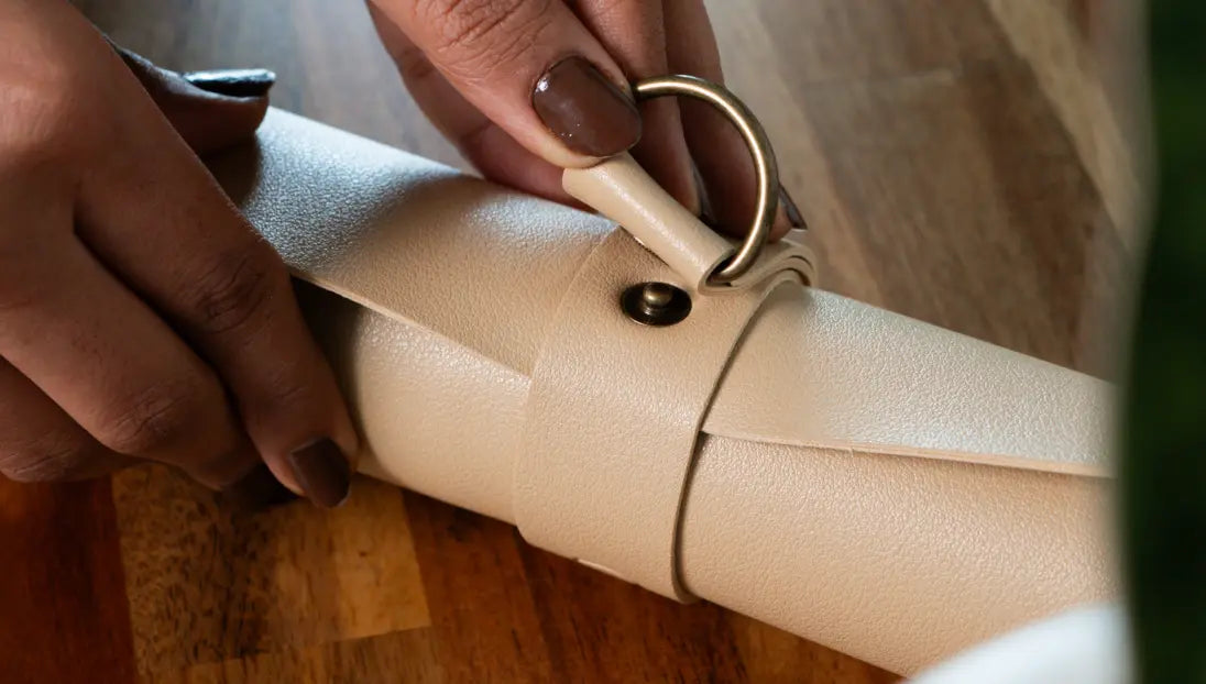 Folded vegan leather potting mat secured with strap for compact storage