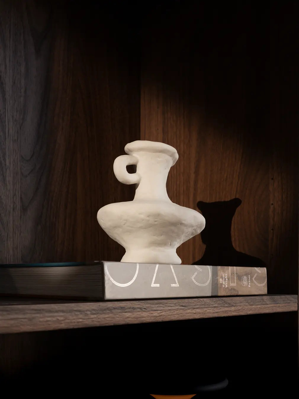 Minimal white Suki Mini Ceramic Vase displayed on a shelf, highlighting its organic shape and ceramic texture.