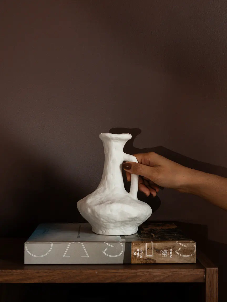 Suki Classic Ceramic Vase styled on books with organic white textured finish.