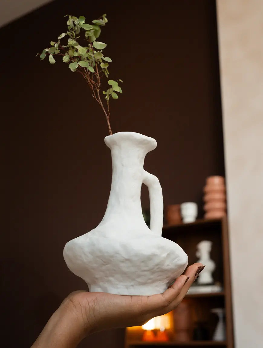 White ceramic flower vase styled with dried stems in a calm, modern interior.