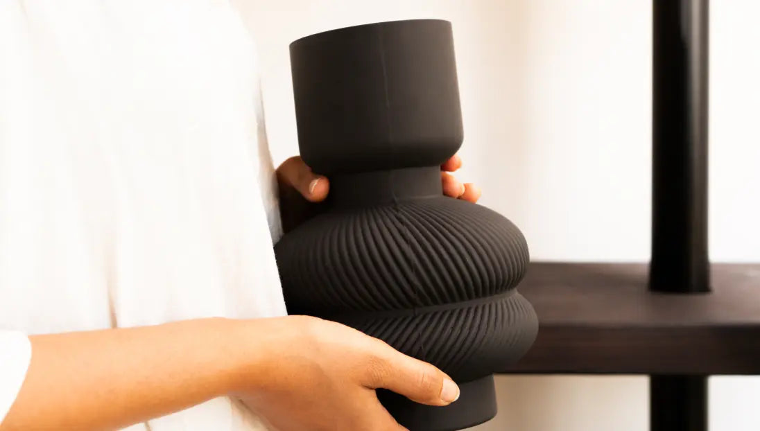 Person holding glass flower vase in matte black for modern and elegant home styling.