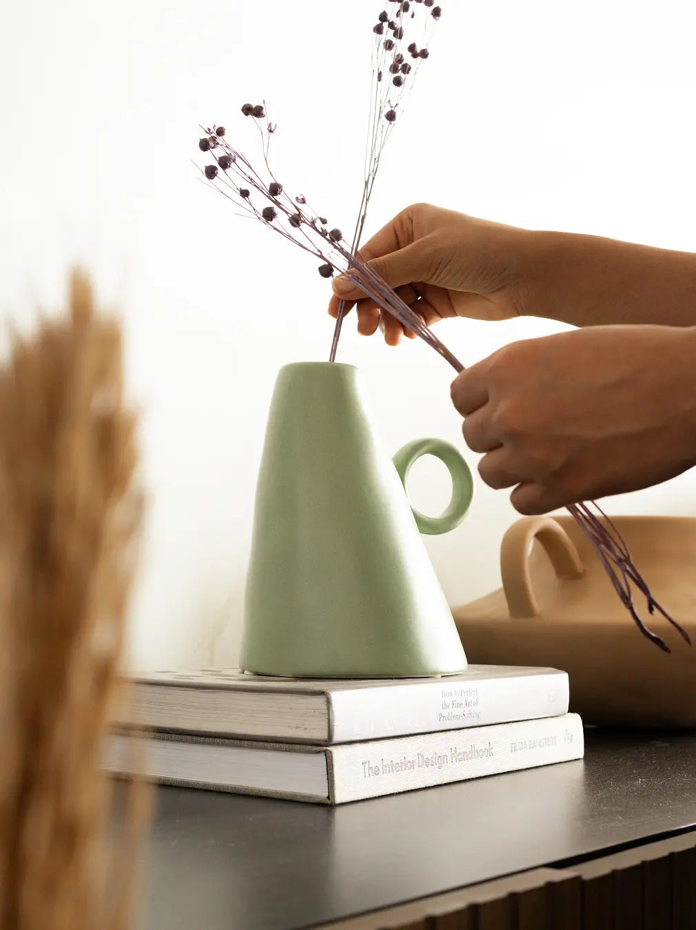 Placing dried stems in stylish ceramic flower vase, modern décor accent.