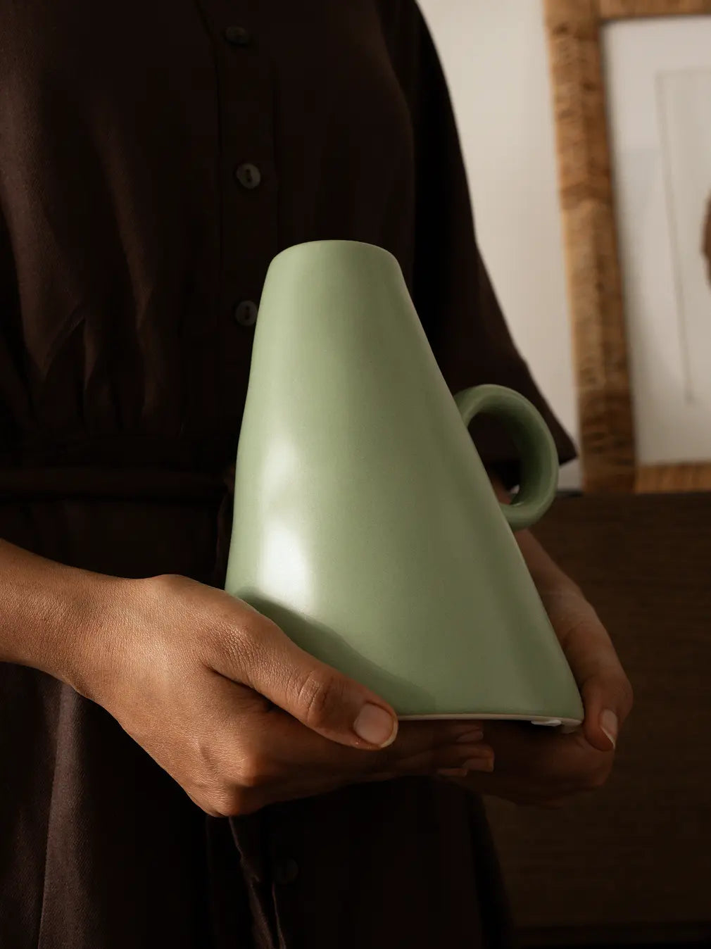 Elegant sage green ceramic vase held in hands, premium home decor.
