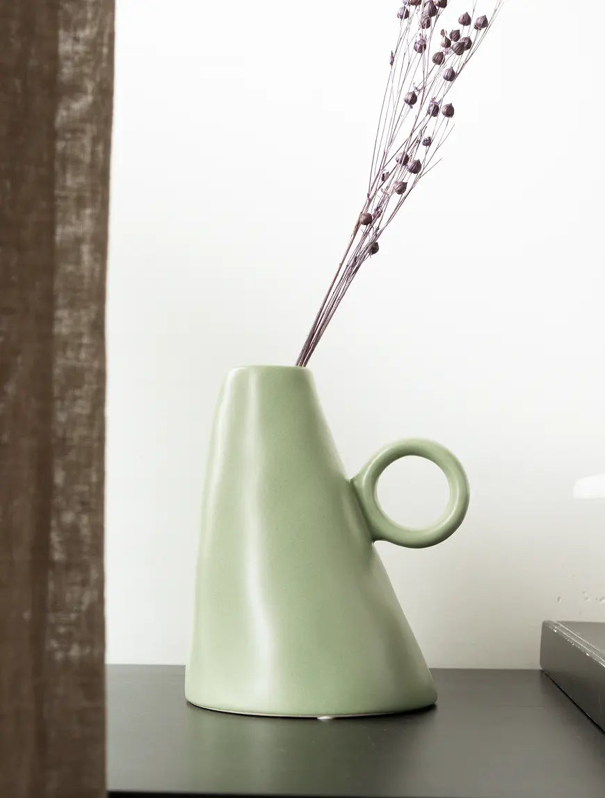 Decorative ceramic vase with dried stems styled in modern interior.