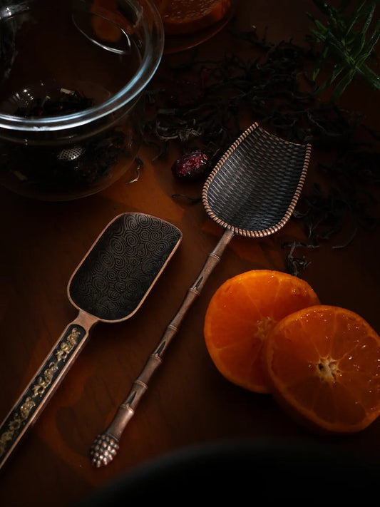 Vintage Spoon set with intricate metalwork, displayed with dried tea leaves and citrus slices