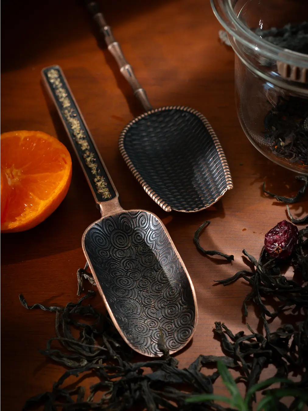 Two Vintage Spoons with ornate patterns, laid on a wooden surface with tea leaves.